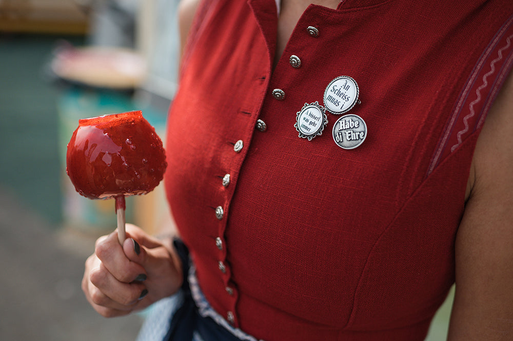 frau-in-rotem-dirndl-mit-ansteckern-mit-spruch-und-rotem-glasierten-apfel